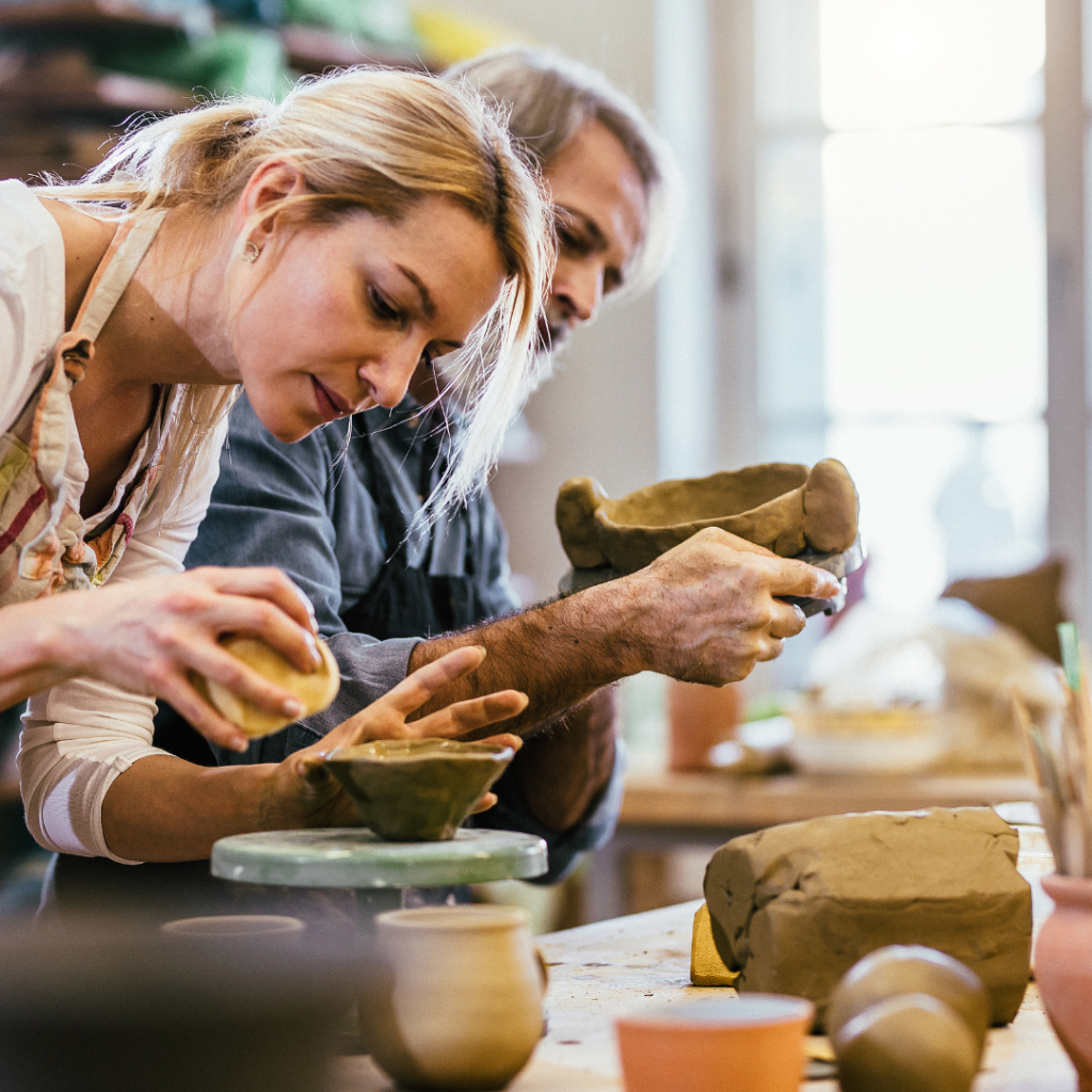 An adult sculpting clay during a pottery class, representing the emotional benefits of artistic endeavours and artistic expression.