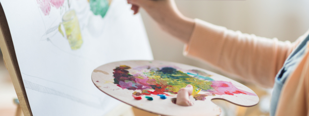 A close-up of hands painting on a canvas, illustrating the tactile and expressive nature of artistic pursuits.
